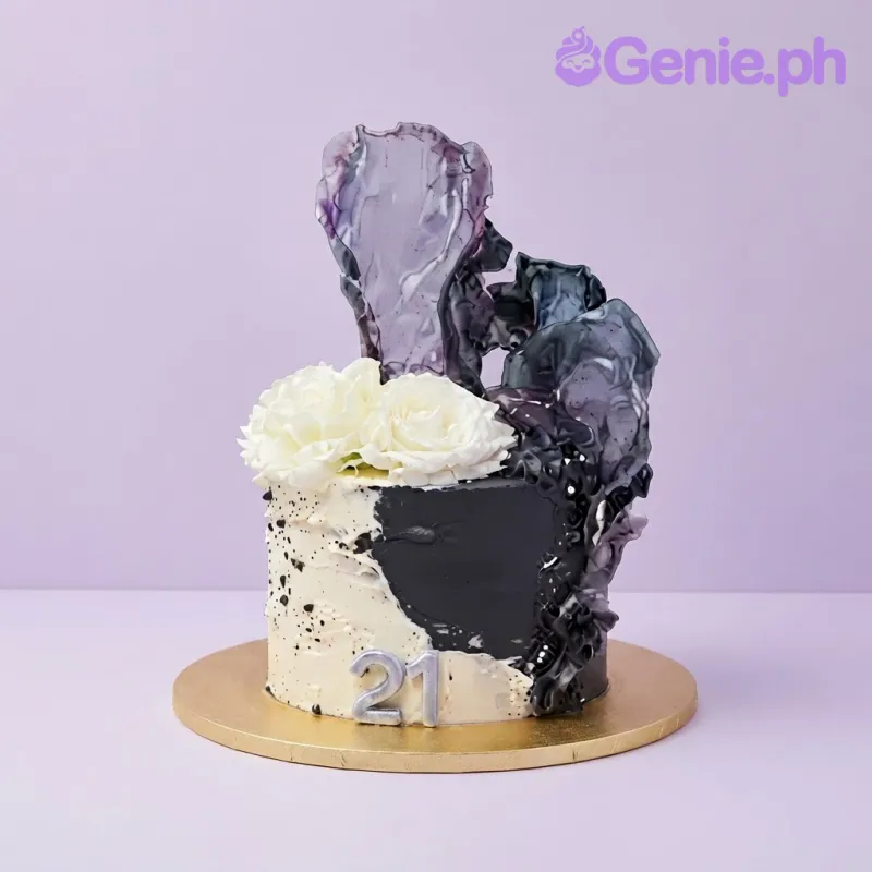 Black and white soft icing cake with a large purple isomalt sail, white flowers, and a silver 21 candle Black and white soft icing cake with a large purple isomalt sail, white flowers, and a silver 21 candle