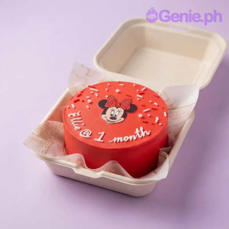 Bright red bento cake with smooth icing, a Minnie Mouse printout on top, white piped text, and scattered sprinkles. Bright red bento cake with smooth icing, a Minnie Mouse printout on top, white piped text, and scattered sprinkles.