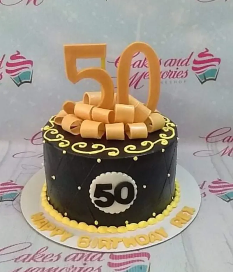 A black and gold 1-tier cake for a 50th Birthday, with gold number 50 toppers, gold ribbon loops, and yellow scrollwork. A black and gold 1-tier cake for a 50th Birthday, with gold number 50 toppers, gold ribbon loops, and yellow scrollwork.