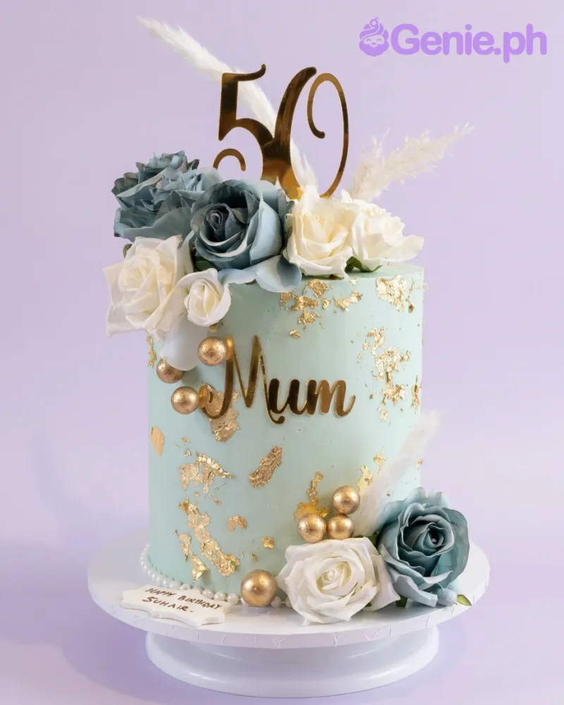Tall mint green cake with gold leaf accents, blue and white artificial roses, gold spheres, and a gold 50 topper. Tall mint green cake with gold leaf accents, blue and white artificial roses, gold spheres, and a gold 50 topper.