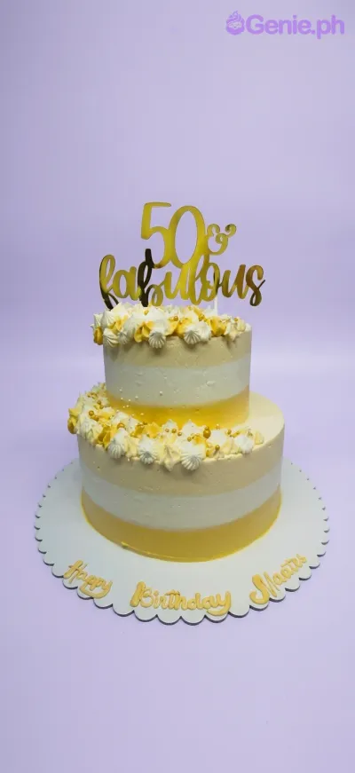 A yellow and white two-tier cake themed for a 50th Birthday, with a gold '50 & Fabulous' topper, piped rosettes, and gold pearls. A yellow and white two-tier cake themed for a 50th Birthday, with a gold '50 & Fabulous' topper, piped rosettes, and gold pearls.