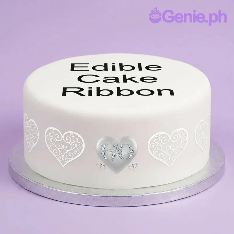 A white 1 Tier round cake for a 60th Anniversary, featuring an edible ribbon with a blue '60' heart design and black text. A white 1 Tier round cake for a 60th Anniversary, featuring an edible ribbon with a blue '60' heart design and black text.