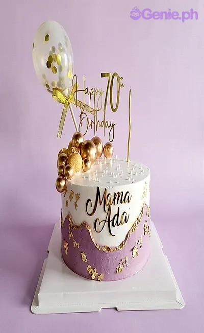 White and purple 70th birthday cake for Mama Ada with gold spheres, a confetti balloon, and gold toppers. White and purple 70th birthday cake for Mama Ada with gold spheres, a confetti balloon, and gold toppers.