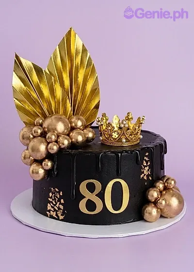 A black and gold 1-tier cake themed around 80th Birthday, featuring a gold crown, gold palm leaves, and gold spheres. A black and gold 1-tier cake themed around 80th Birthday, featuring a gold crown, gold palm leaves, and gold spheres.
