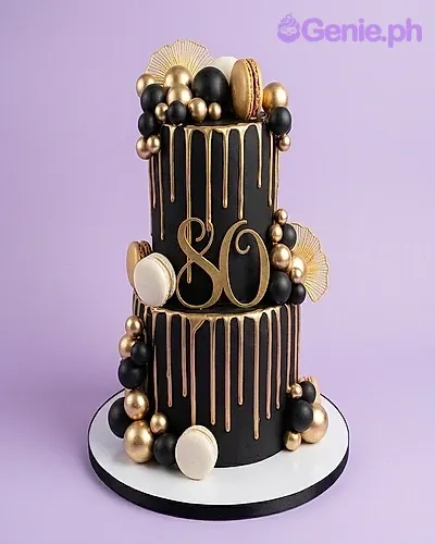 A black and gold 2-tier 80th Birthday cake with a gold number 80 topper, gold drip, black and gold spheres. A black and gold 2-tier 80th Birthday cake with a gold number 80 topper, gold drip, black and gold spheres.