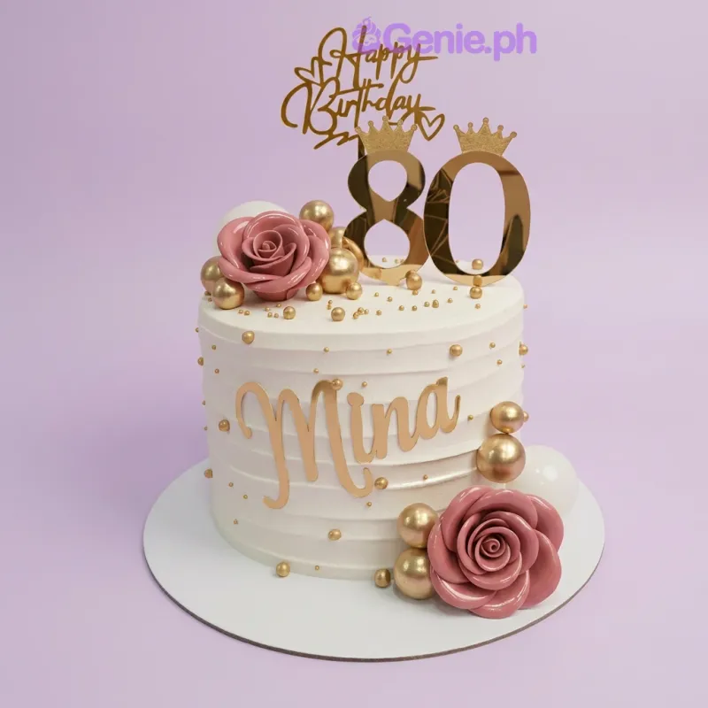 A white 1-tier 80th birthday cake with gold accents, pink roses, and gold spheres. A white 1-tier 80th birthday cake with gold accents, pink roses, and gold spheres.
