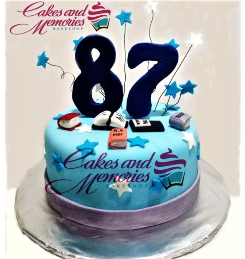 Light blue fondant cake for an 87th birthday featuring large navy blue number toppers, fondant books, and blue and white stars. Light blue fondant cake for an 87th birthday featuring large navy blue number toppers, fondant books, and blue and white stars.