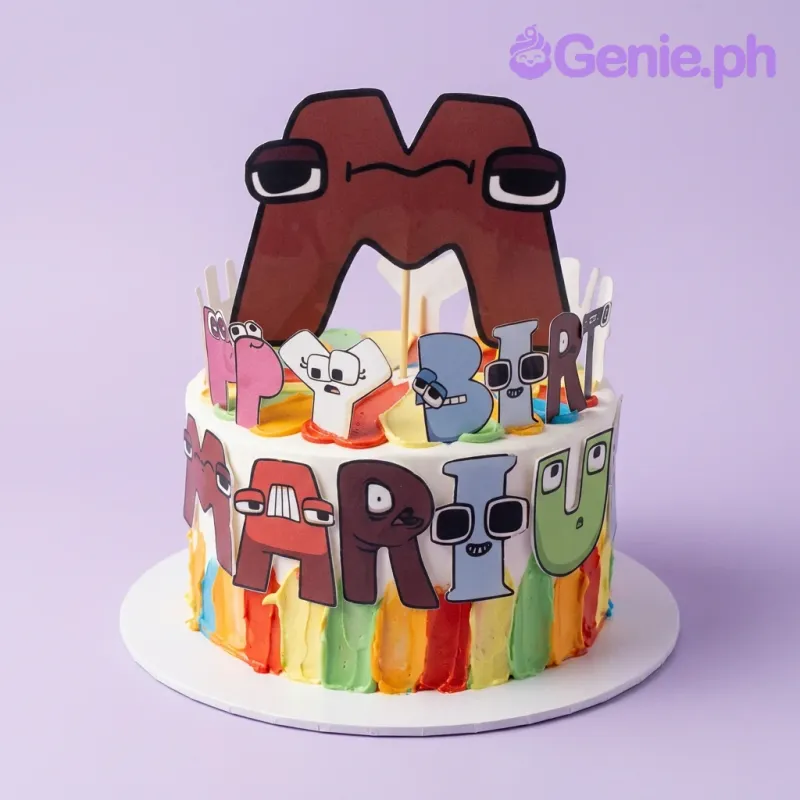 Alphabet Lore themed birthday cake with colorful icing stripes and character printouts including a large letter M topper. Alphabet Lore themed birthday cake with colorful icing stripes and character printouts including a large letter M topper.