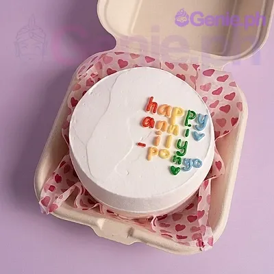 A white Bento cake for Anniversary, featuring colorful fondant letters 'Happy Anniv Ily Ponyo' and a heart-patterned liner. A white Bento cake for Anniversary, featuring colorful fondant letters 'Happy Anniv Ily Ponyo' and a heart-patterned liner.