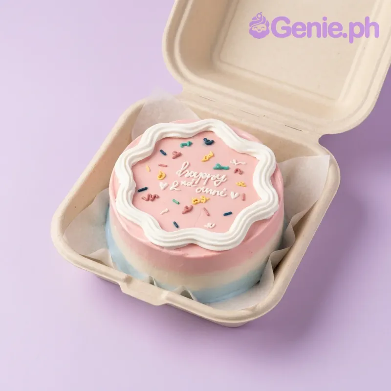 A pink and blue bento cake themed around Anniversary, featuring a 'Happy 2nd anni' message and a white wavy icing border with colorful sprinkles. A pink and blue bento cake themed around Anniversary, featuring a 'Happy 2nd anni' message and a white wavy icing border with colorful sprinkles.