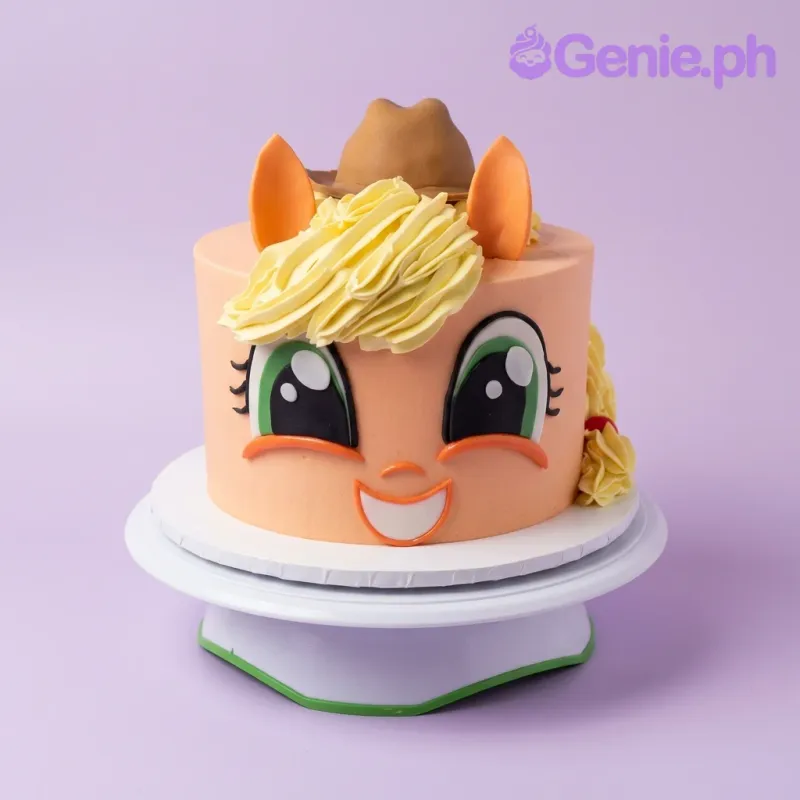 An orange, yellow, and brown 1 Tier cake themed around Applejack, featuring a brown cowboy hat, large green eyes, and yellow piped hair swirls. An orange, yellow, and brown 1 Tier cake themed around Applejack, featuring a brown cowboy hat, large green eyes, and yellow piped hair swirls.