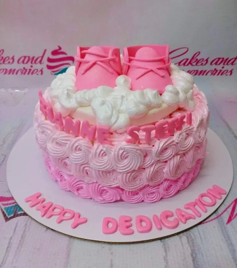 Pink ombre rosette cake with pink fondant baby shoes and white icing clouds on top. Pink ombre rosette cake with pink fondant baby shoes and white icing clouds on top.