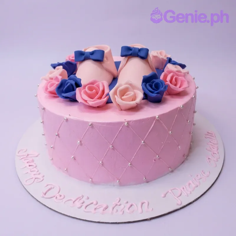Pink baby shoes cake with pink and blue edible roses and silver dragees on a quilted icing pattern. Pink baby shoes cake with pink and blue edible roses and silver dragees on a quilted icing pattern.