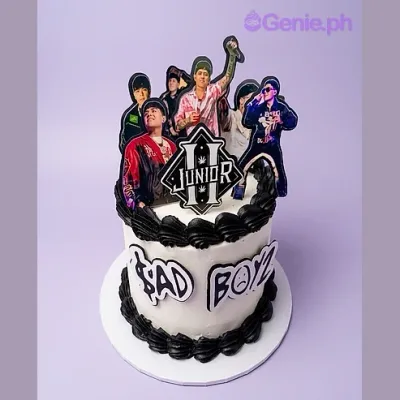 One tier white soft-iced cake with a Junior logo printout, four band member printouts, black piped borders, and a piped message One tier white soft-iced cake with a Junior logo printout, four band member printouts, black piped borders, and a piped message