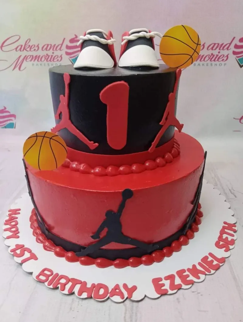 Two-tier basketball themed birthday cake in red and black with Jordan silhouettes, fondant sneakers, and basketball toppers. Two-tier basketball themed birthday cake in red and black with Jordan silhouettes, fondant sneakers, and basketball toppers.