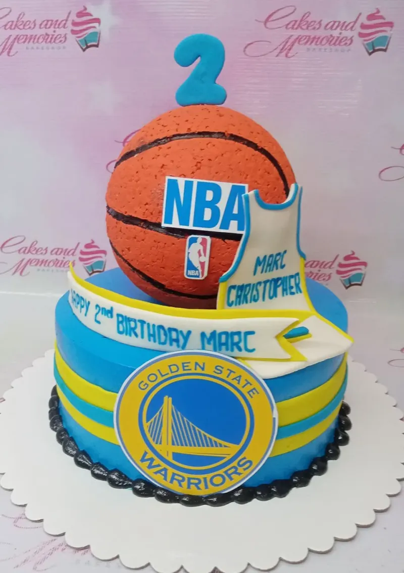 Blue Golden State Warriors basketball themed cake with a large 3D basketball topper and jersey cutout. Blue Golden State Warriors basketball themed cake with a large 3D basketball topper and jersey cutout.