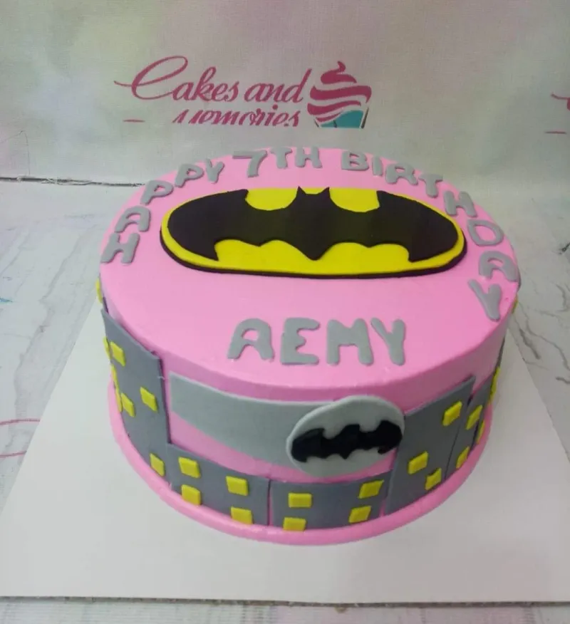 Pink Batman themed birthday cake with a large yellow and black Batman logo on top and a city skyline gumpaste panel around the side. Pink Batman themed birthday cake with a large yellow and black Batman logo on top and a city skyline gumpaste panel around the side.