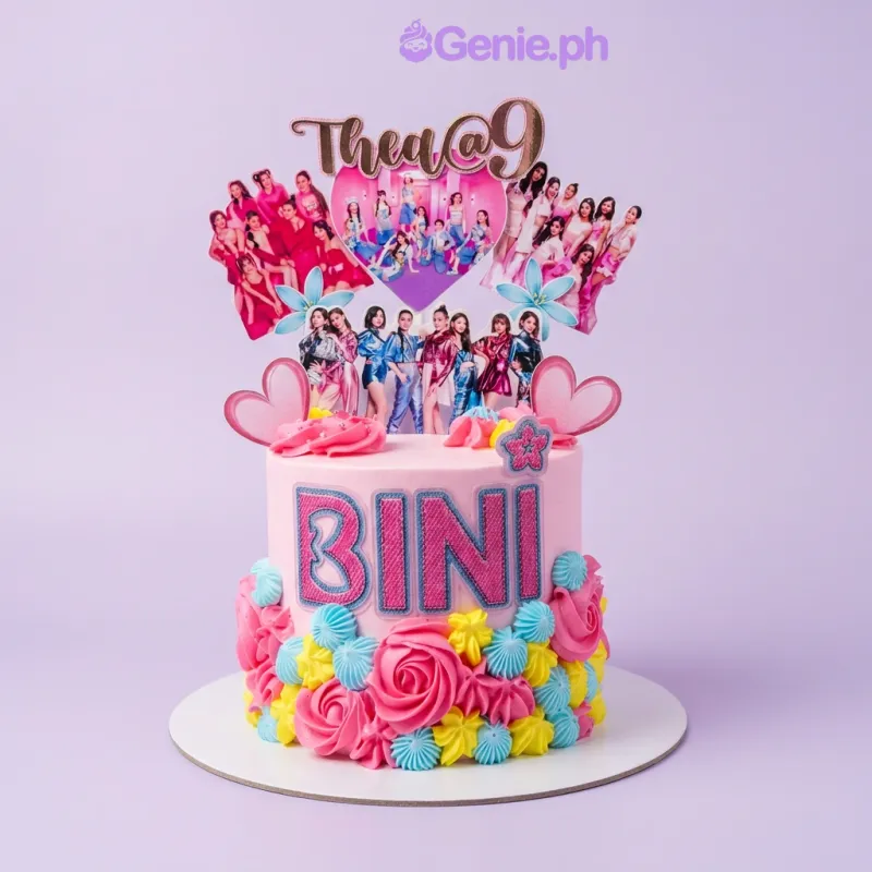 Bini Kpop cake design — 1 layer soft icing cake in pink — with large printed BINI group cutout with heart, piped pink rosettes, piped light blue swirls, piped yellow flowers, and custom "Thea@9" message Bini Kpop cake design — 1 layer soft icing cake in pink — with large printed BINI group cutout with heart, piped pink rosettes, piped light blue swirls, piped yellow flowers, and custom "Thea@9" message
