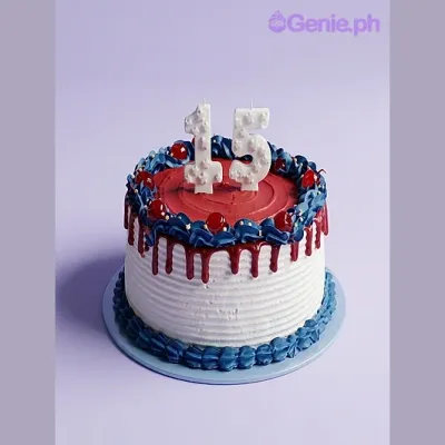 Round cake with white icing, red drip, blue border, and number 15 candles on top Round cake with white icing, red drip, blue border, and number 15 candles on top