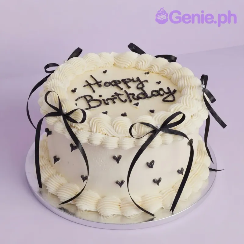 White 1 tier soft icing cake with black ribbon bows, piped rosettes, and black heart accents White 1 tier soft icing cake with black ribbon bows, piped rosettes, and black heart accents
