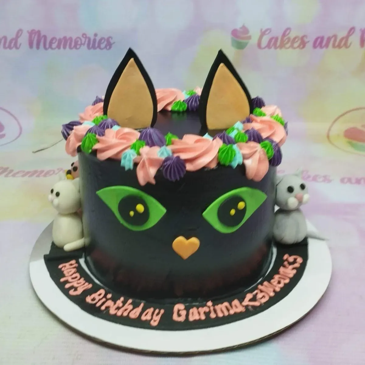 Black cat themed birthday cake with green eyes, orange heart nose, and colorful icing rosettes on top. Black cat themed birthday cake with green eyes, orange heart nose, and colorful icing rosettes on top.
