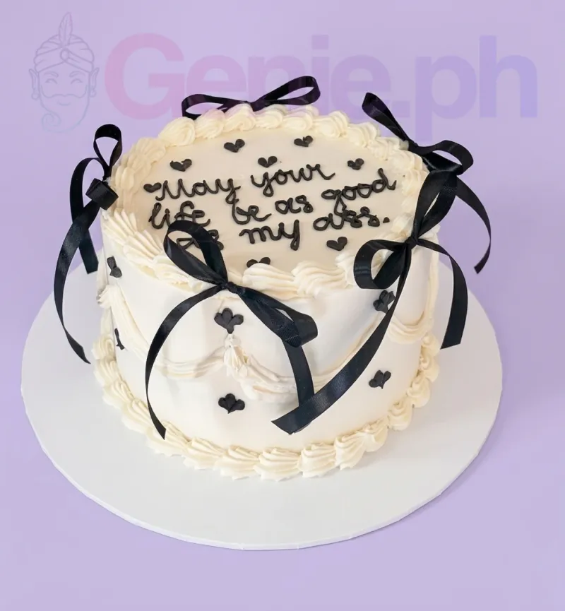 A white and black 1-tier cake themed around minimalism, featuring a black piped message, black satin ribbons, and white piped borders. A white and black 1-tier cake themed around minimalism, featuring a black piped message, black satin ribbons, and white piped borders.