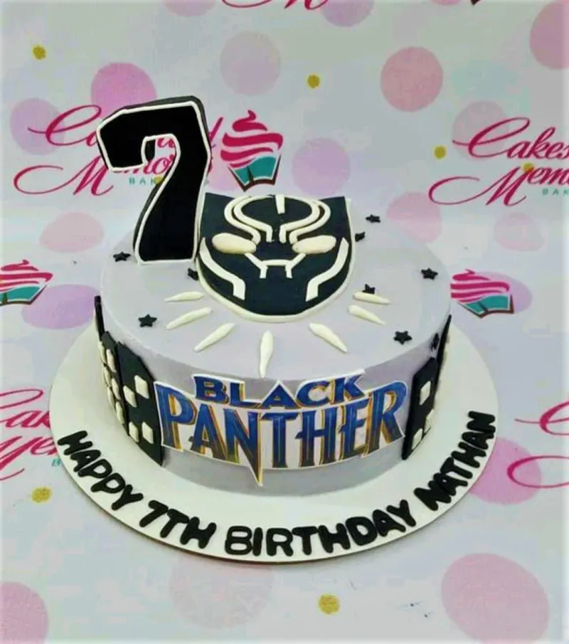 Black Panther themed birthday cake with a large number 7 topper and character logo on light purple icing. Black Panther themed birthday cake with a large number 7 topper and character logo on light purple icing.