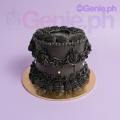 A black 1-tier cake, vintage themed, with piped black ruffles, rosettes, swags, and white pearl accents on a gold base. A black 1-tier cake, vintage themed, with piped black ruffles, rosettes, swags, and white pearl accents on a gold base.