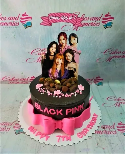 Black and pink Blackpink themed birthday cake with character printouts, chocolate decorations, and a large pink fondant bow. Black and pink Blackpink themed birthday cake with character printouts, chocolate decorations, and a large pink fondant bow.