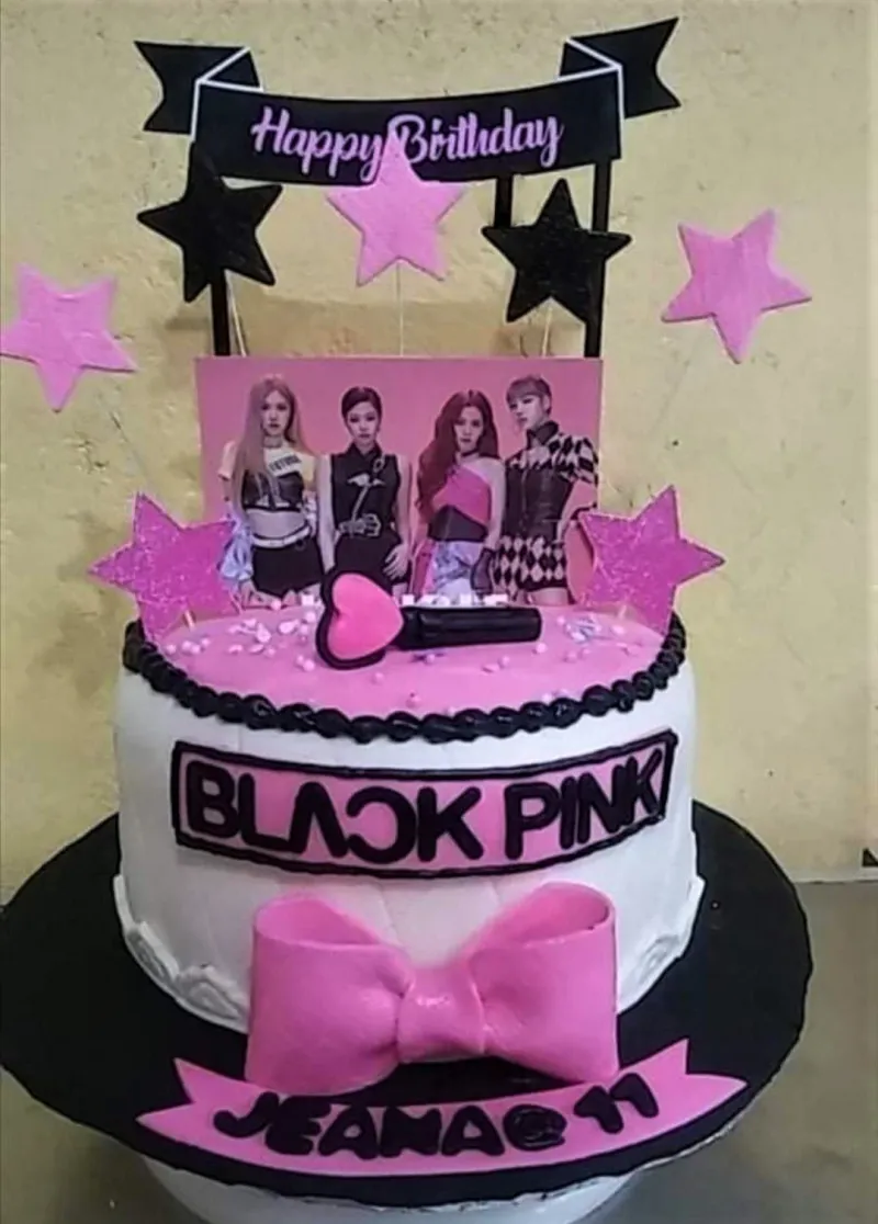 Blackpink themed birthday cake with pink and black stars, a group photo printout, and a large pink fondant bow. Blackpink themed birthday cake with pink and black stars, a group photo printout, and a large pink fondant bow.