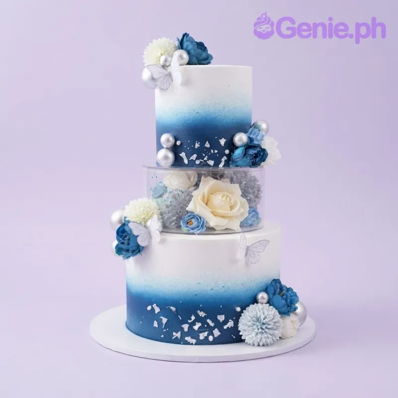 Blue and white gradient 2-tier cake with soft icing, blue fondant flowers, and silver spheres Blue and white gradient 2-tier cake with soft icing, blue fondant flowers, and silver spheres