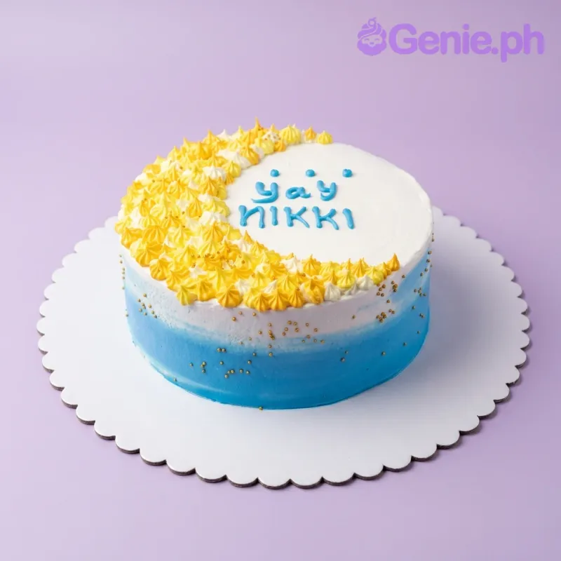 A blue and white gradient 1-tier cake with yellow icing rosettes, gold sprinkles, and 'yay NIKKI' in blue icing. A blue and white gradient 1-tier cake with yellow icing rosettes, gold sprinkles, and 'yay NIKKI' in blue icing.