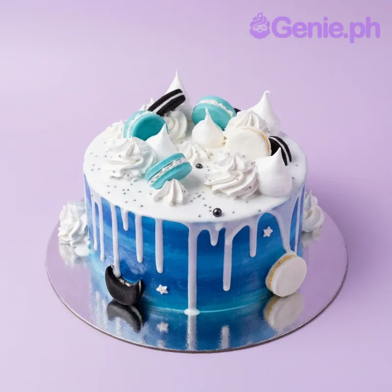 A blue and white 1-tier cake with a blue gradient design, featuring teal and white macarons, meringue kisses, and a white chocolate drip. A blue and white 1-tier cake with a blue gradient design, featuring teal and white macarons, meringue kisses, and a white chocolate drip.