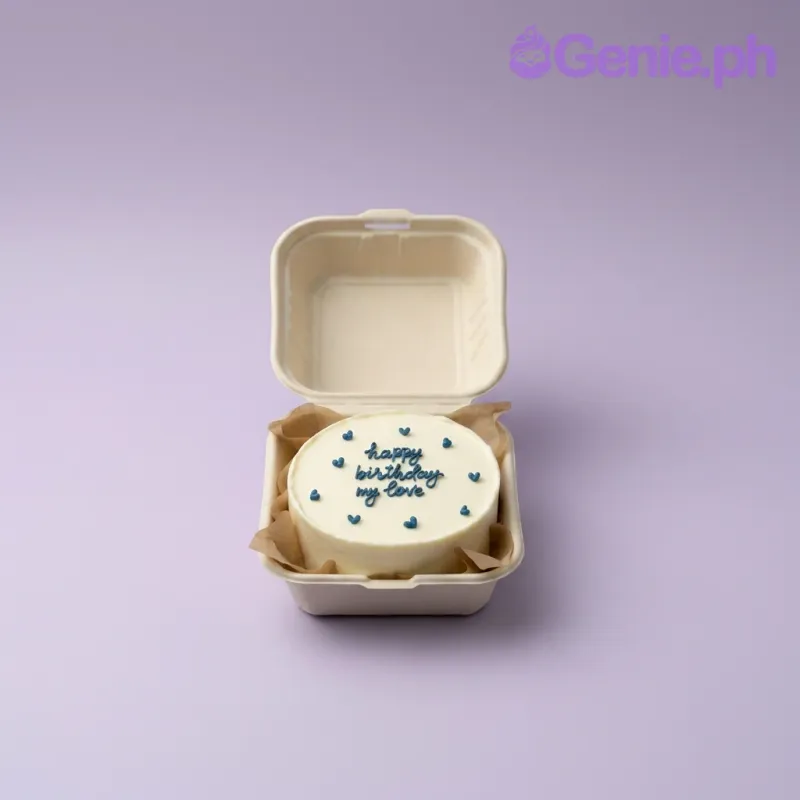 A white Bento cake themed around Blue Minimalist, featuring blue piped hearts and a handwritten message in blue icing. A white Bento cake themed around Blue Minimalist, featuring blue piped hearts and a handwritten message in blue icing.