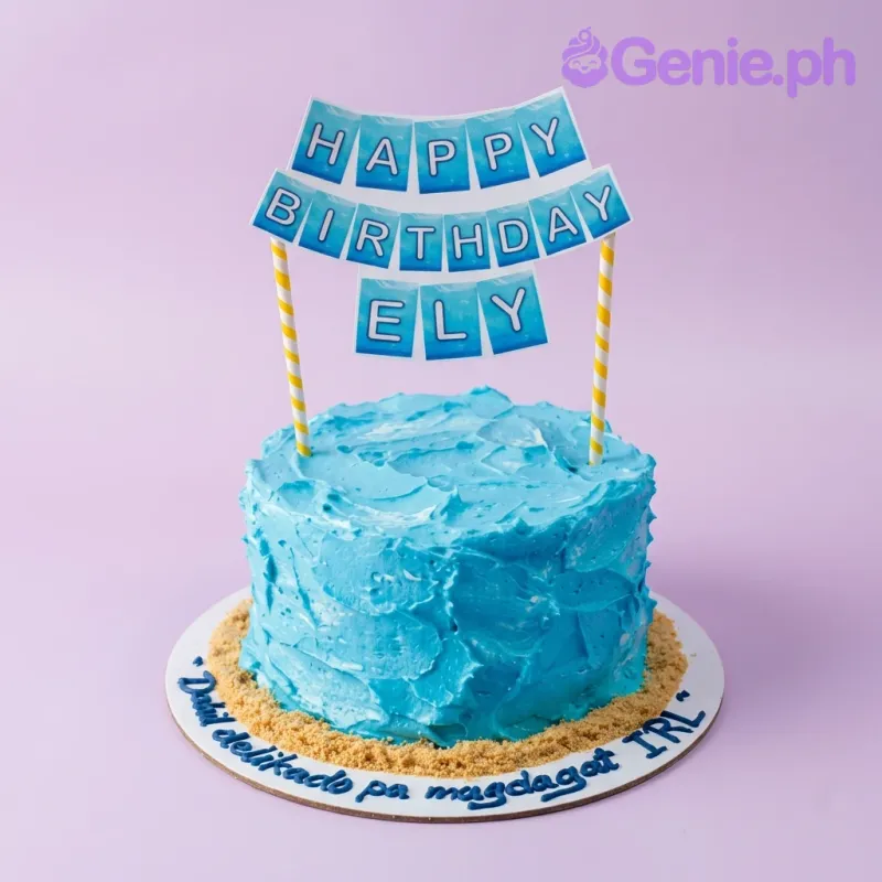 A blue and yellow 1-tier cake themed around Blue Ocean, featuring a blue 'Happy Birthday Ely' banner and yellow crushed cookie sand. A blue and yellow 1-tier cake themed around Blue Ocean, featuring a blue 'Happy Birthday Ely' banner and yellow crushed cookie sand.