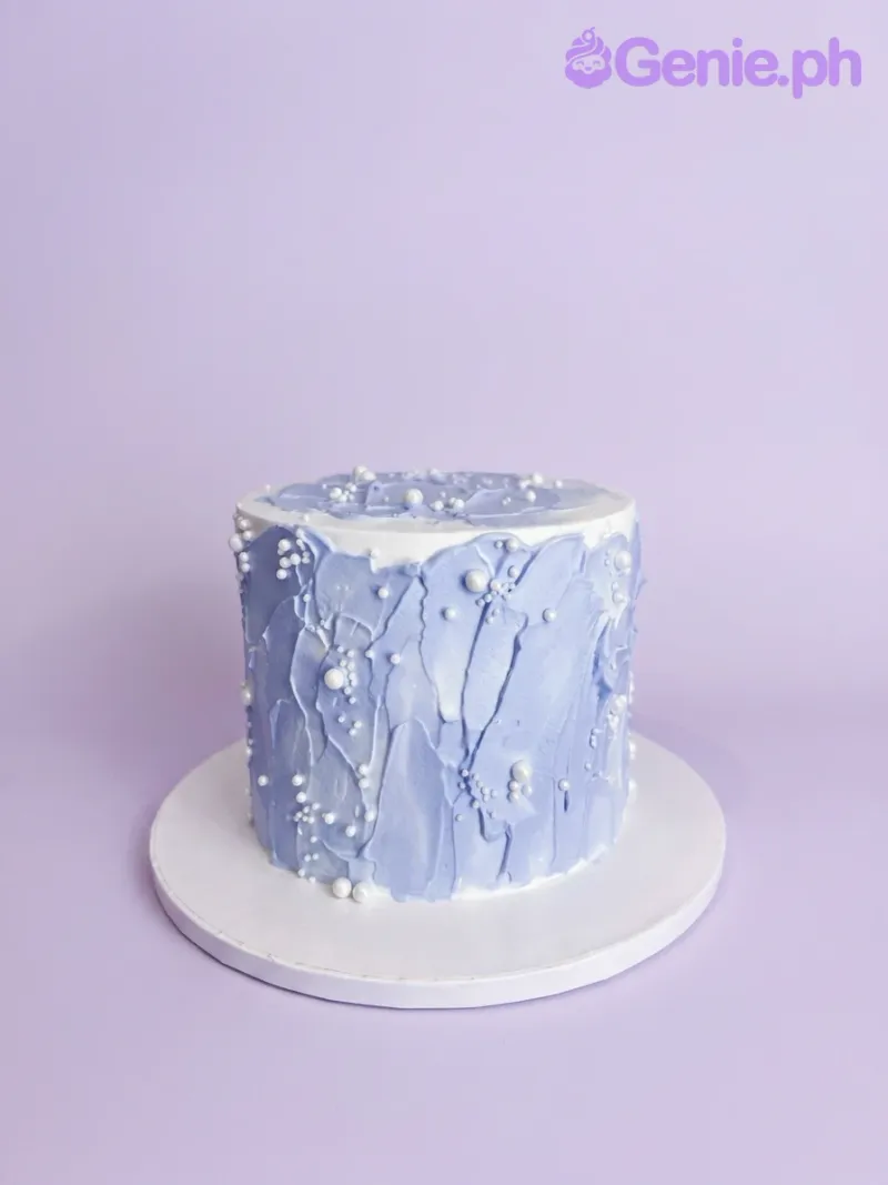 A white and light blue 1 Tier cake with textured light blue palette knife icing and white pearl sprinkles. A white and light blue 1 Tier cake with textured light blue palette knife icing and white pearl sprinkles.