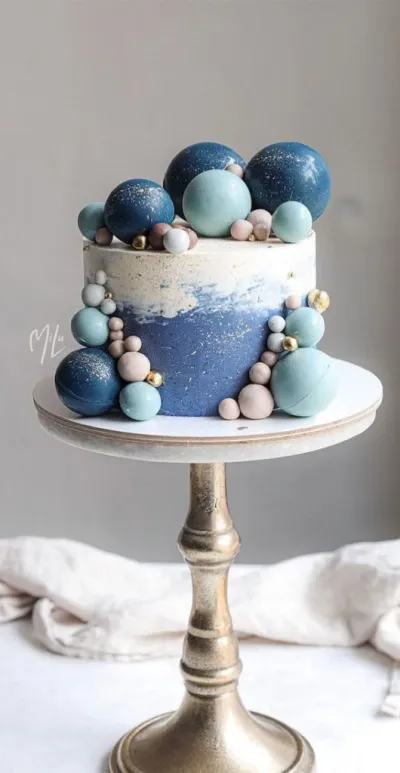 Navy blue and white 1-tier cake with smooth soft icing, dark blue plastic spheres, and gold leaf accents Navy blue and white 1-tier cake with smooth soft icing, dark blue plastic spheres, and gold leaf accents