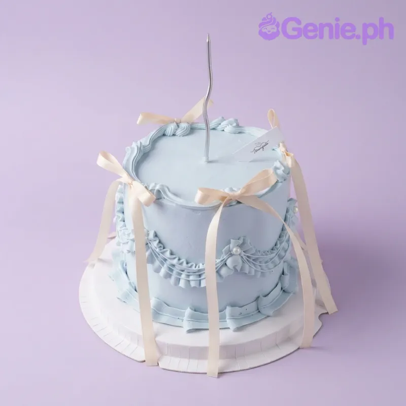 A light blue 1 Tier cake themed Blue Vintage, featuring a silver wavy candle, ruffles, swags, and cream ribbons.