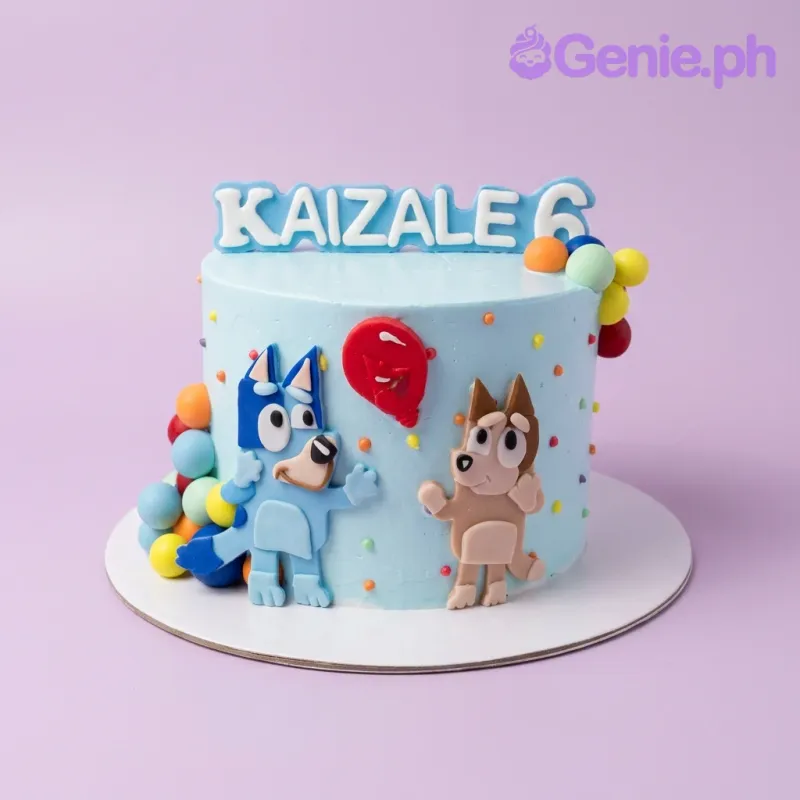 A light blue 1-tier cake themed around Bluey, featuring fondant characters Bluey and Bingo, a red balloon, and colorful fondant balls. A light blue 1-tier cake themed around Bluey, featuring fondant characters Bluey and Bingo, a red balloon, and colorful fondant balls.