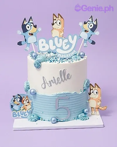 A white and light blue 1-tier cake themed around Bluey, featuring Bluey and Bingo character cutouts and blue pearl sprinkles. A white and light blue 1-tier cake themed around Bluey, featuring Bluey and Bingo character cutouts and blue pearl sprinkles.