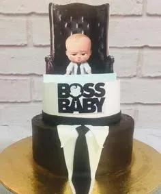 Brown 2-tier birthday cake with smooth soft icing, Boss Baby figure topper, and shirt panel decor Brown 2-tier birthday cake with smooth soft icing, Boss Baby figure topper, and shirt panel decor