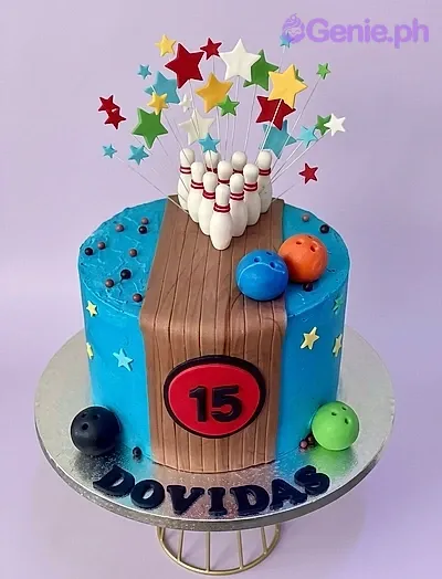 A blue and brown 1-tier Bowling Birthday cake, featuring bowling pins, colorful balls, a wooden lane, and stars. A blue and brown 1-tier Bowling Birthday cake, featuring bowling pins, colorful balls, a wooden lane, and stars.