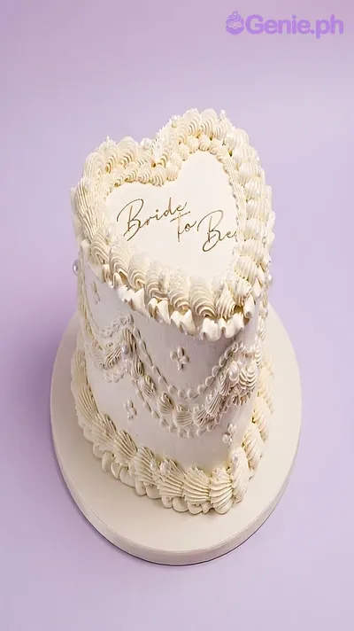 White heart-shaped cake with soft icing, piped borders, pearl accents, and a Bride to Be printout topper White heart-shaped cake with soft icing, piped borders, pearl accents, and a Bride to Be printout topper