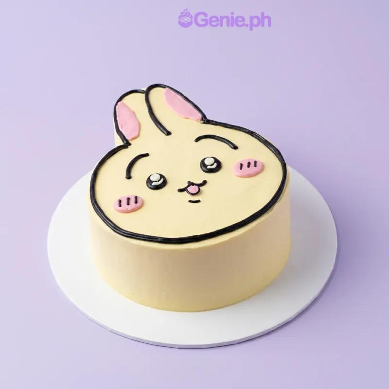 Light yellow bunny face cake with black piped eyes and pink cheeks Light yellow bunny face cake with black piped eyes and pink cheeks
