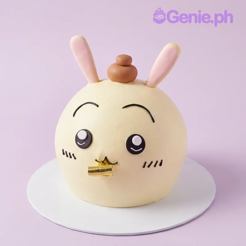 One tier ivory soft-iced cake with edible bunny ears, a brown top knot, a gold object, and icing eyes, eyebrows, whiskers, and mouth One tier ivory soft-iced cake with edible bunny ears, a brown top knot, a gold object, and icing eyes, eyebrows, whiskers, and mouth