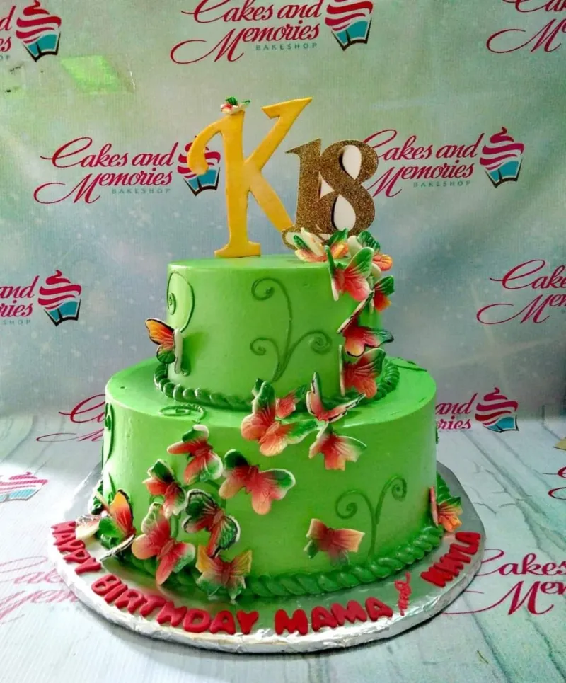 Two-tier green birthday cake decorated with colorful edible butterflies and large gold number 18 and letter K toppers. Two-tier green birthday cake decorated with colorful edible butterflies and large gold number 18 and letter K toppers.