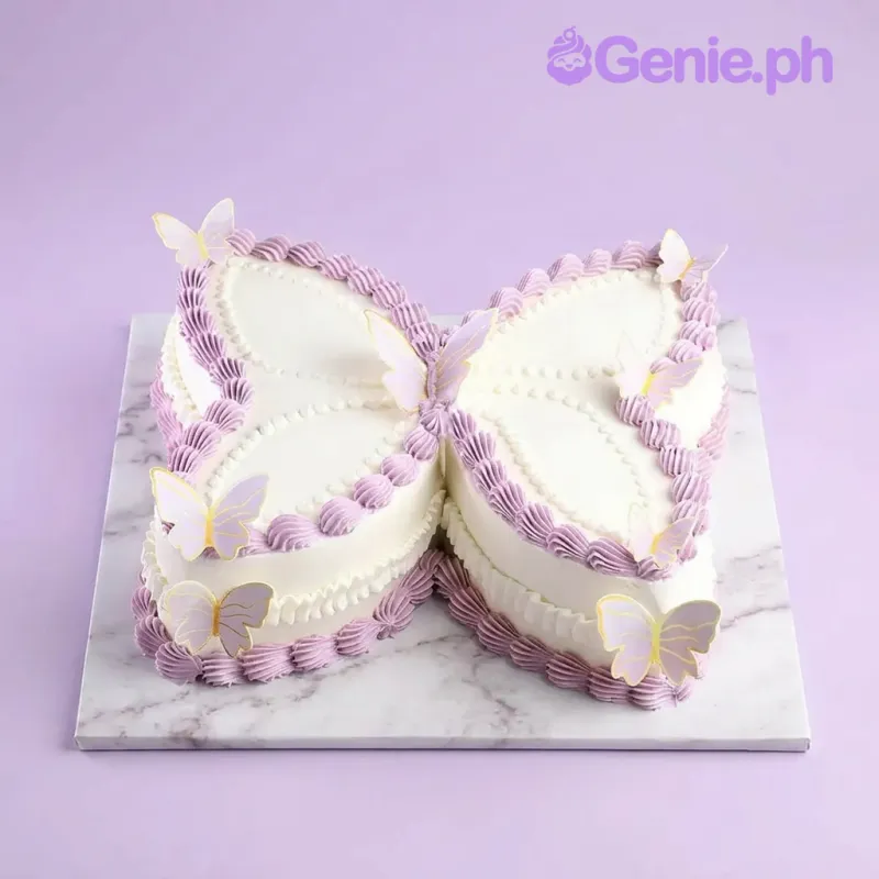 White butterfly shaped cake with lavender piped borders and butterfly cutouts White butterfly shaped cake with lavender piped borders and butterfly cutouts