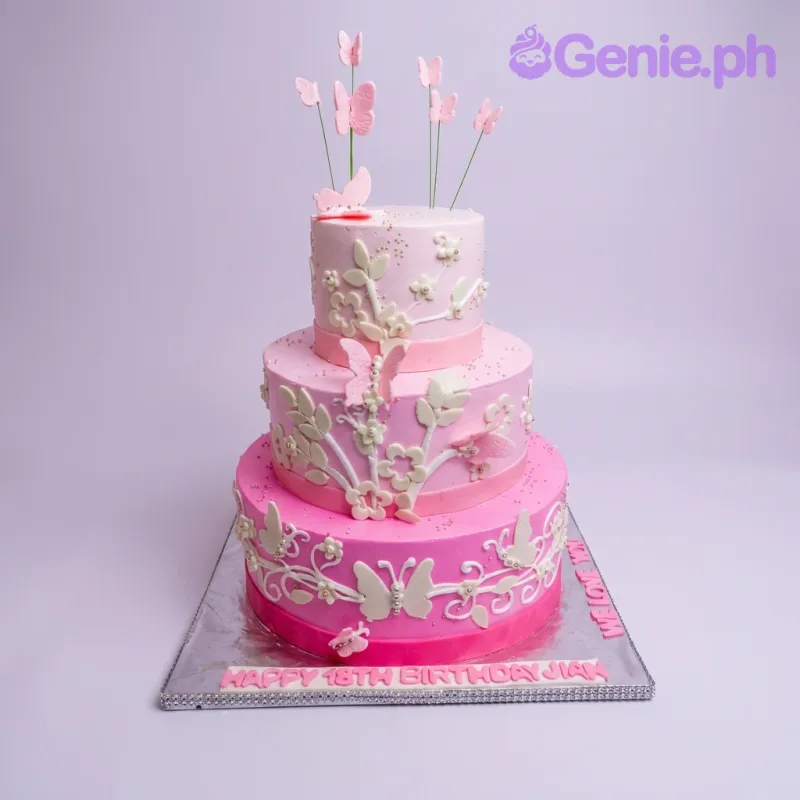 A pink gradient three-tier fondant cake themed around Butterfly Floral, featuring pink butterflies on wires and white gumpaste flowers and leaves. A pink gradient three-tier fondant cake themed around Butterfly Floral, featuring pink butterflies on wires and white gumpaste flowers and leaves.