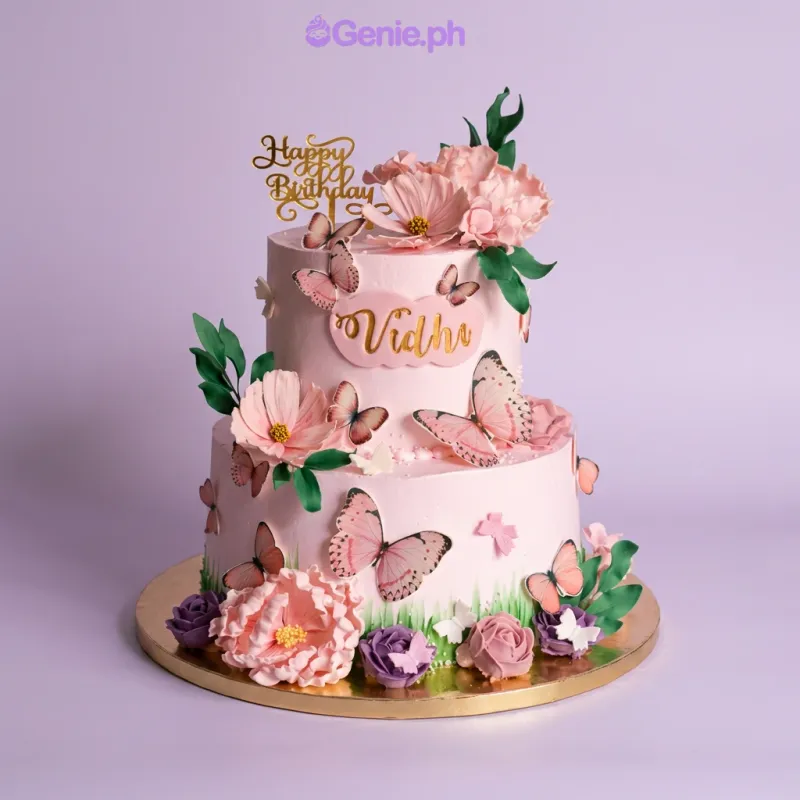 Light pink 2-tier cake with soft icing, butterfly printouts, edible flowers, and a gold Happy Birthday topper Light pink 2-tier cake with soft icing, butterfly printouts, edible flowers, and a gold Happy Birthday topper