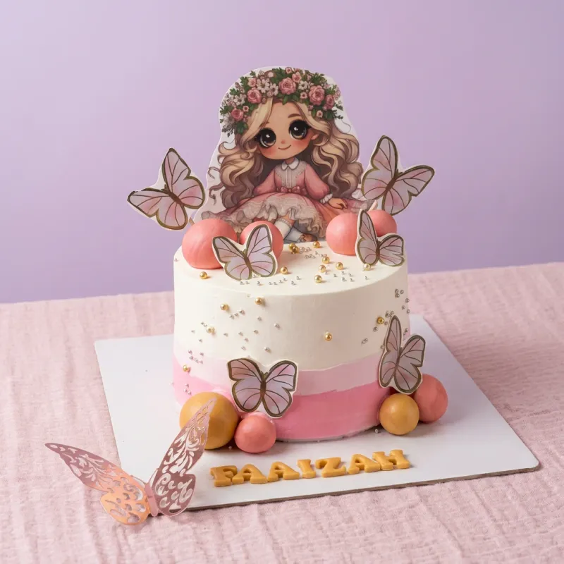 White and pink 1-tier cake with a girl character printout, butterfly cutouts, and gold name topper White and pink 1-tier cake with a girl character printout, butterfly cutouts, and gold name topper